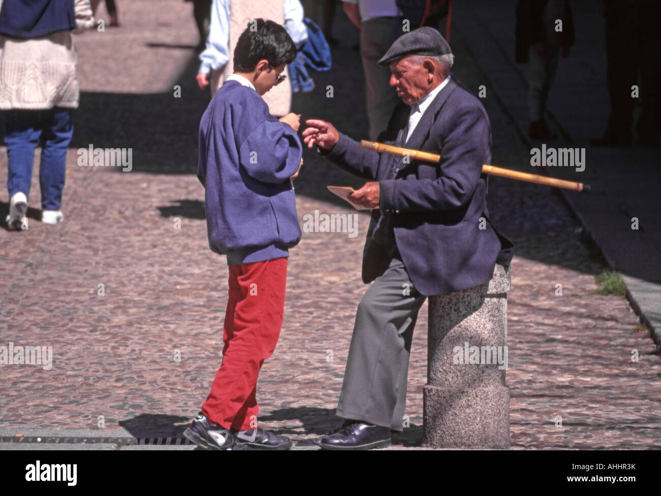 El Escorial, Spain. Young boy talking to Old Man with walking stick Stock Photo