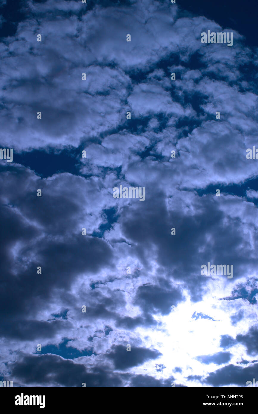 Sun coming through the clouds in a blue sky Stock Photo - Alamy