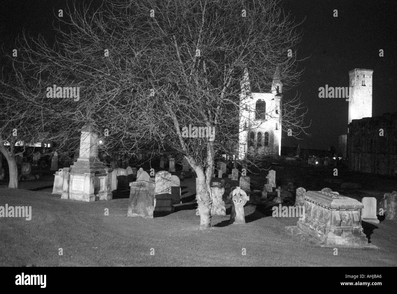 Ruins of eastern gable, graves, tree and St. Rule's Tower in the grounds of St. Andrews Cathedral at night. St. Andrews, Fife, Scotland, UK. Stock Photo