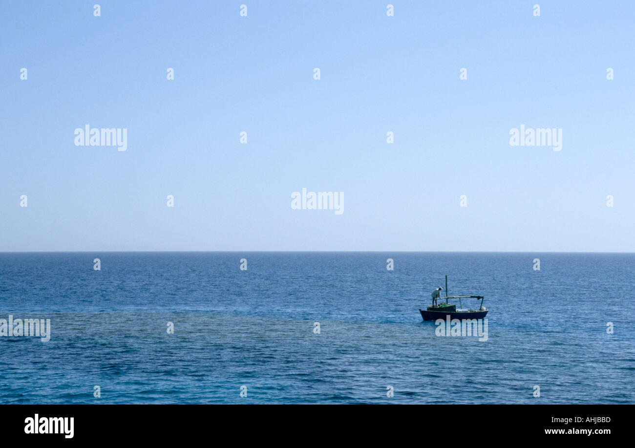 Man in traditional wooden boat on blue water of Red Sea under clear ...