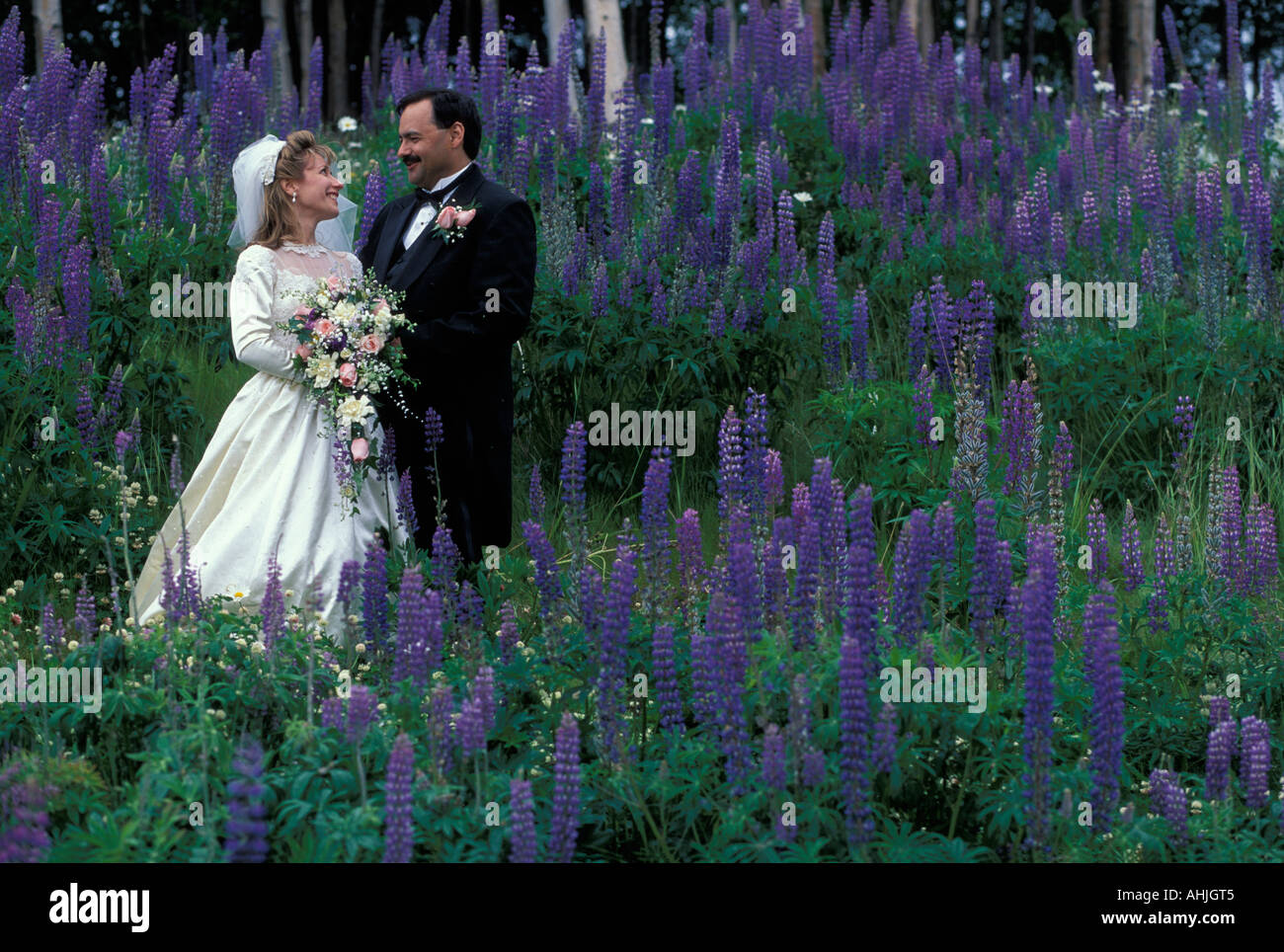 USA Alaska Anchorage MR Gail David Springer stand in wildflowers on their summer wedding day Stock Photo