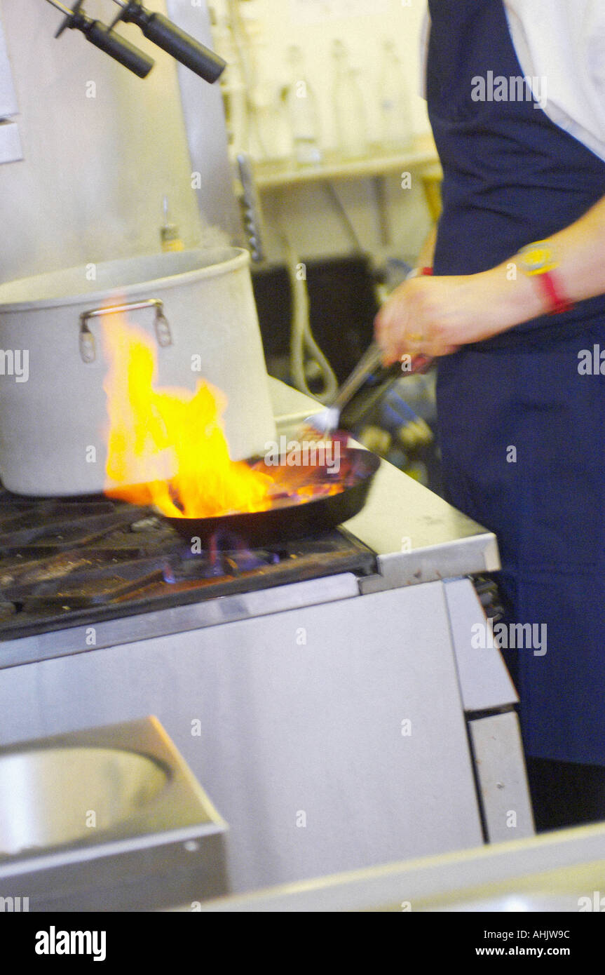 Frying pan on a gas stove with dramatic flames from flambéing with the ...