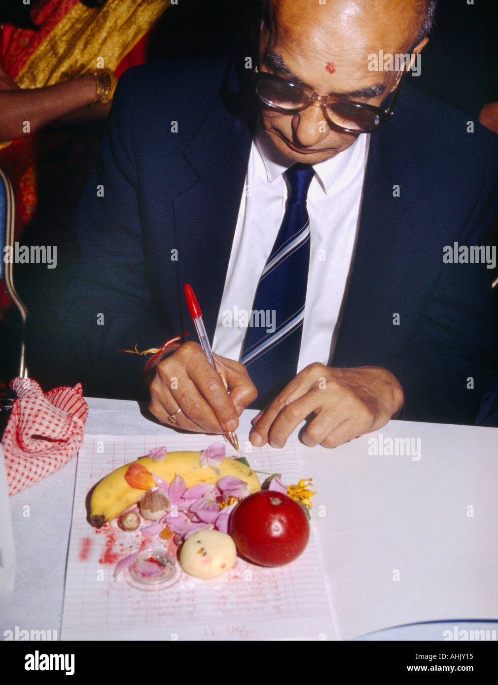 Man Writing in Red Ink on Page Performing Chopda Puja During Diwali Signifying the Start of the new Financial year in the Hindu Calendar Greenford Tow Stock Photo