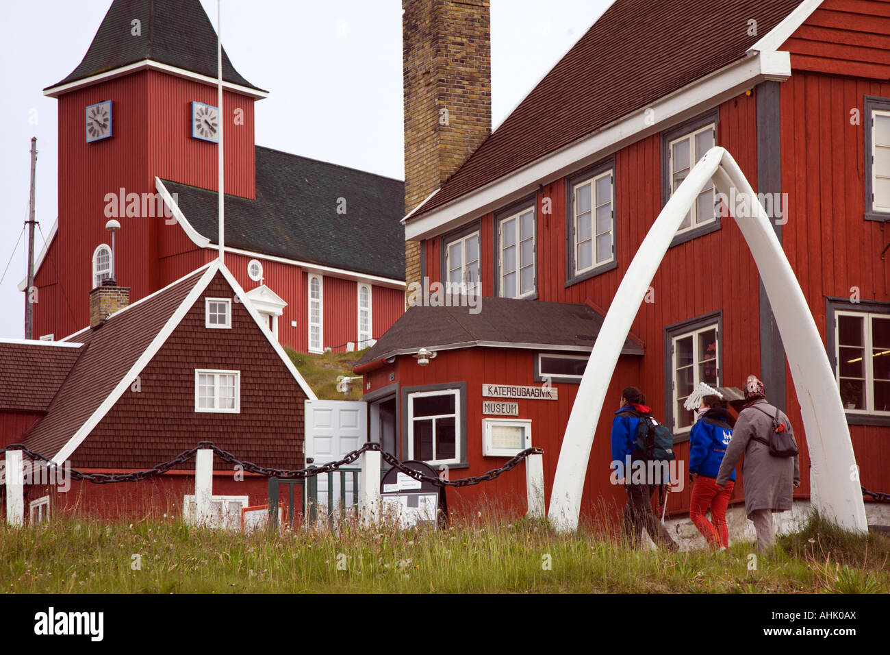 People walk through traditional whale jawbone arch entrance to local museum and Church at Sisimiut on west coast of Greenland Stock Photo