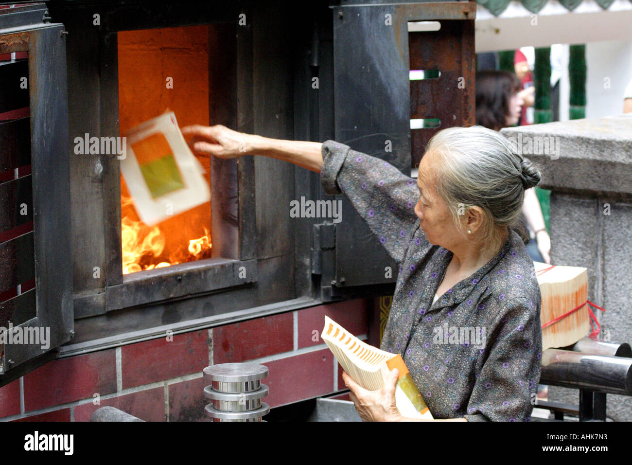 Elderly Chinese Woman Burning Fake Money to Honor Dead Ancestors, Man Mo Temple, Hong Kong, China Stock Photo