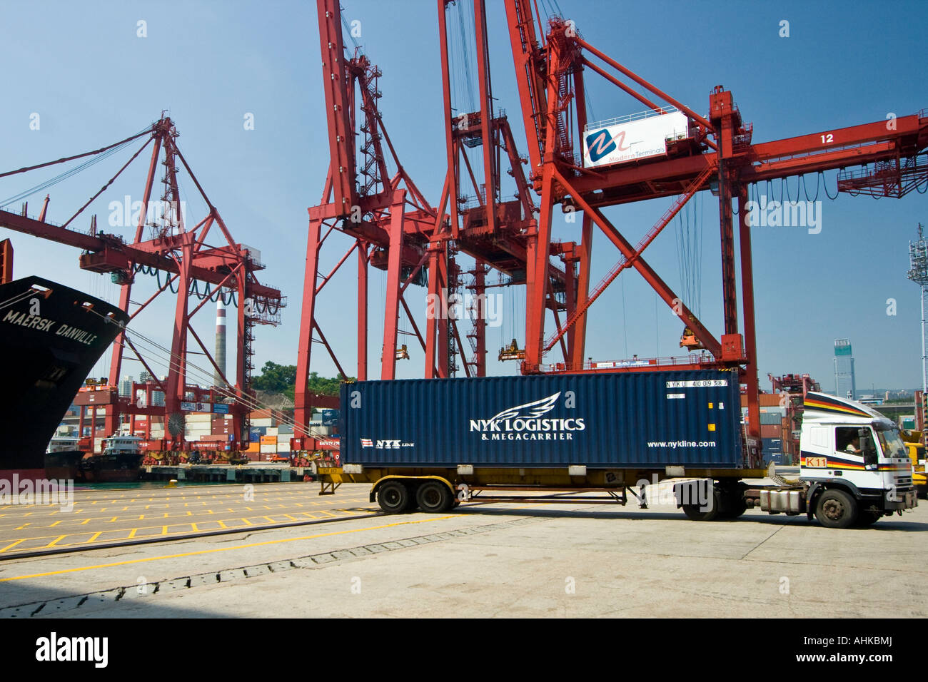 Crane Loaded Truck Driving with NYK Logistics Shipping Container, Hong Kong Port Docks Stock Photo