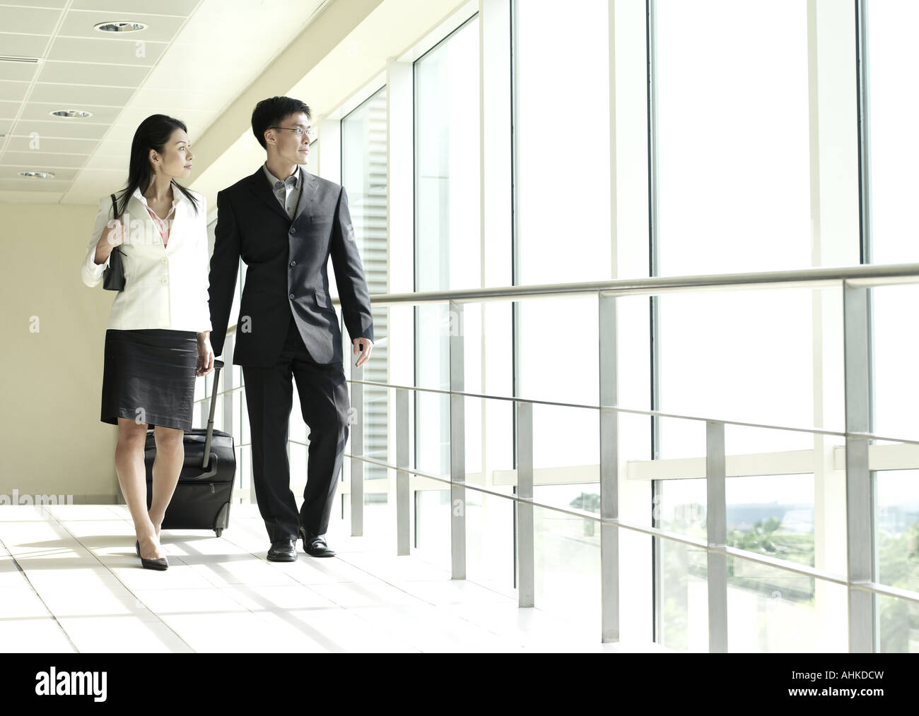 Businesswoman and businessman walking down corridor Stock Photo - Alamy