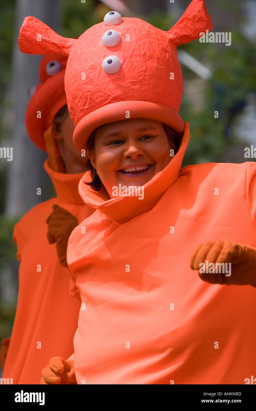 Lady dressed as an orange alien and having fun on a carnival float Stock Photo