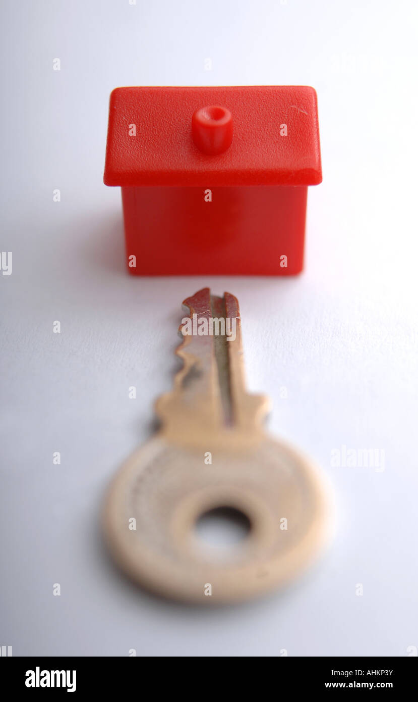 A red monopoly house with a key pointing towards the front illustrating house price and interest rate increase or decrease Stock Photo
