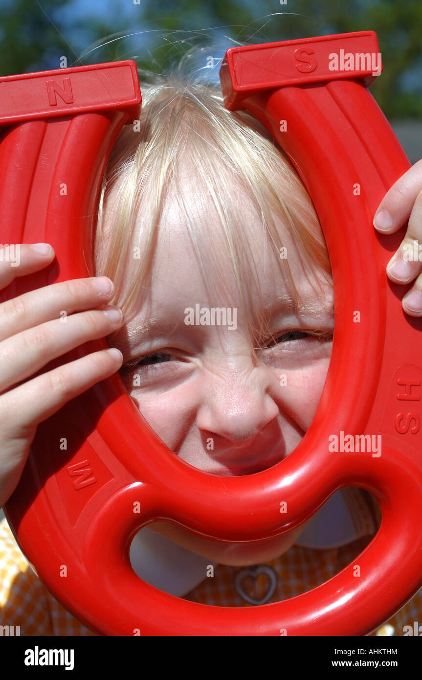 A young girl playing with a large red plastic magnet during an outdoor ...