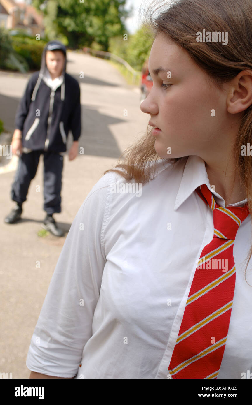 a girl dressed in school uniform being followed by a boy Stock Photo
