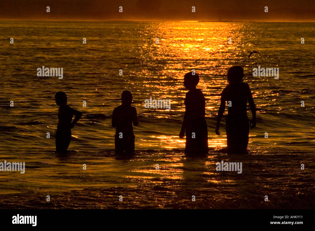 Children playing in the water at sunset Stock Photo - Alamy