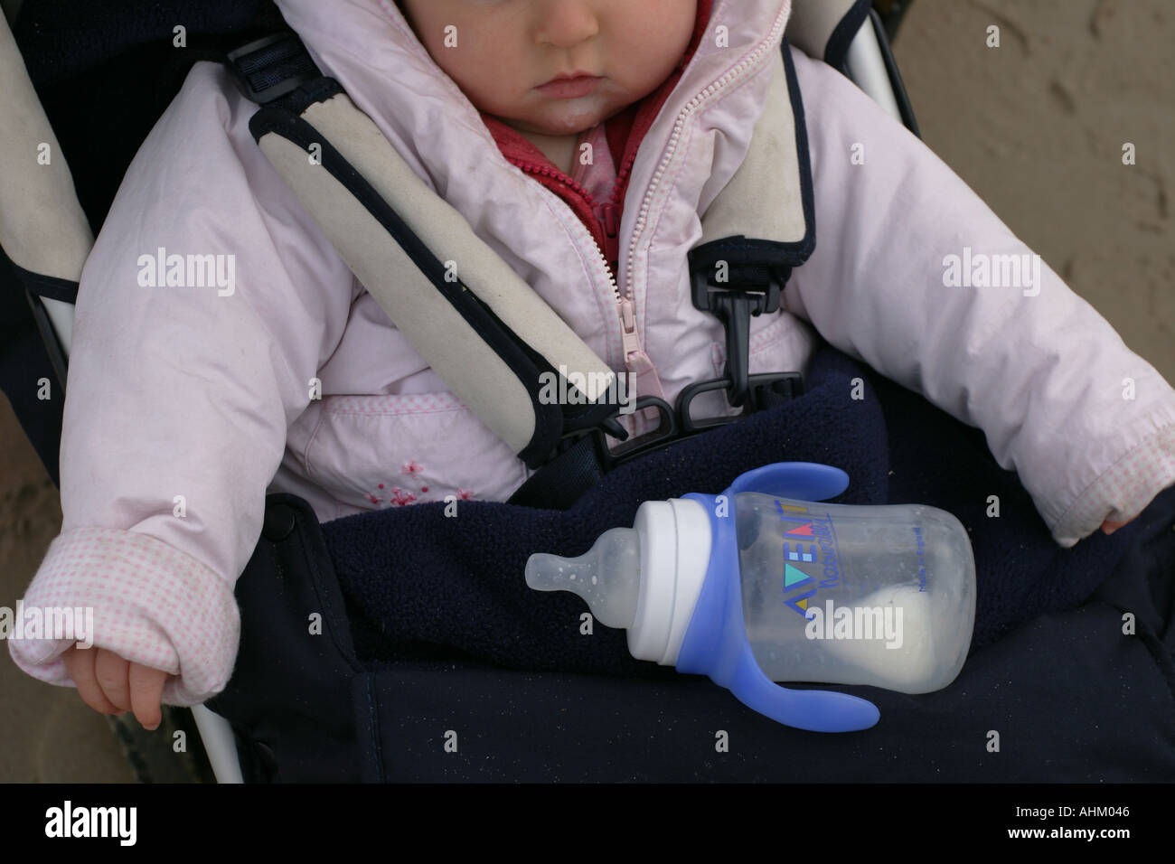 A baby in her buggy with an empty baby milk bottle, Northumbria, UK. Stock Photo