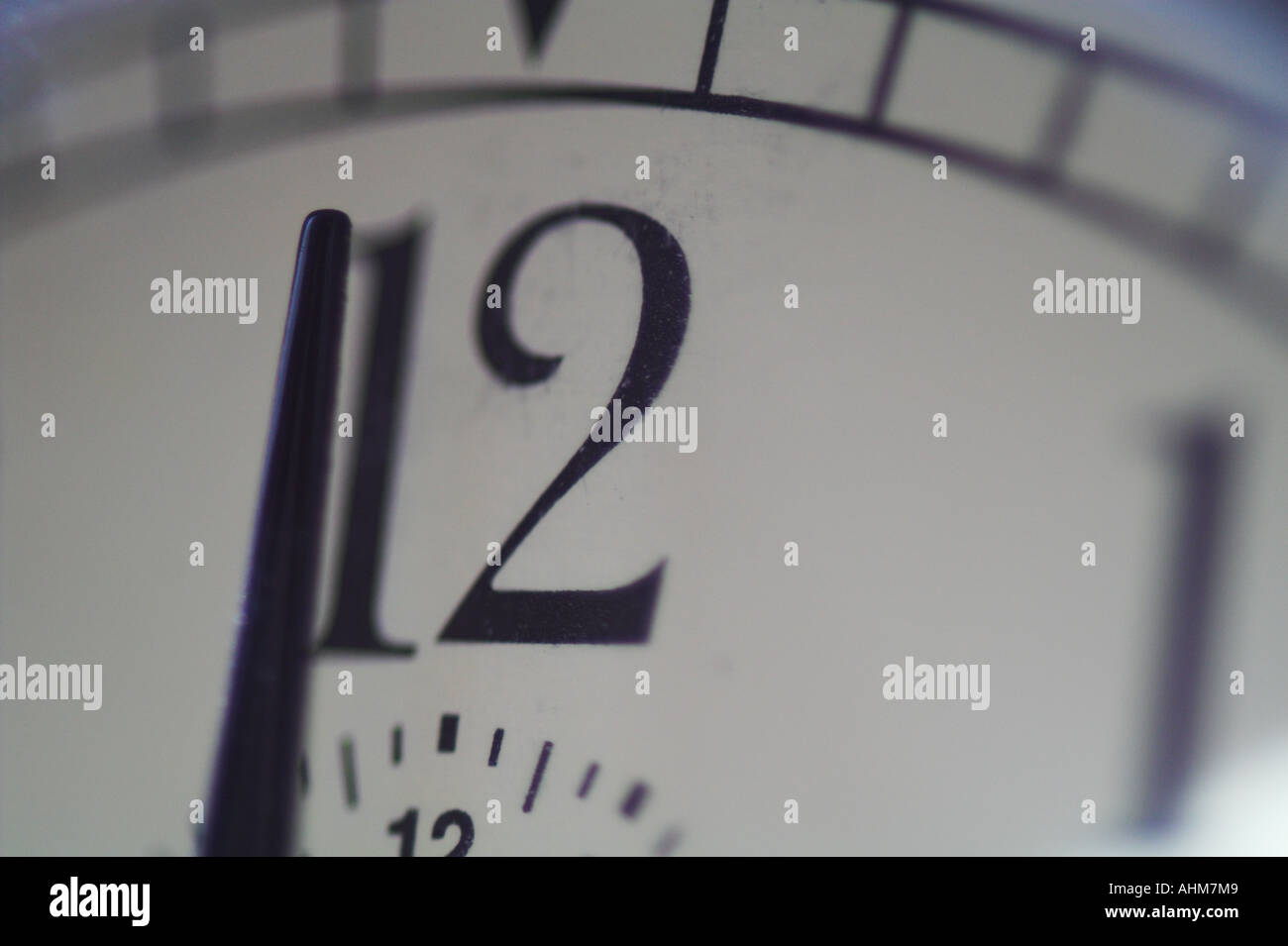 Closeup of clock with hands near 12 o'clock with sun light on the
