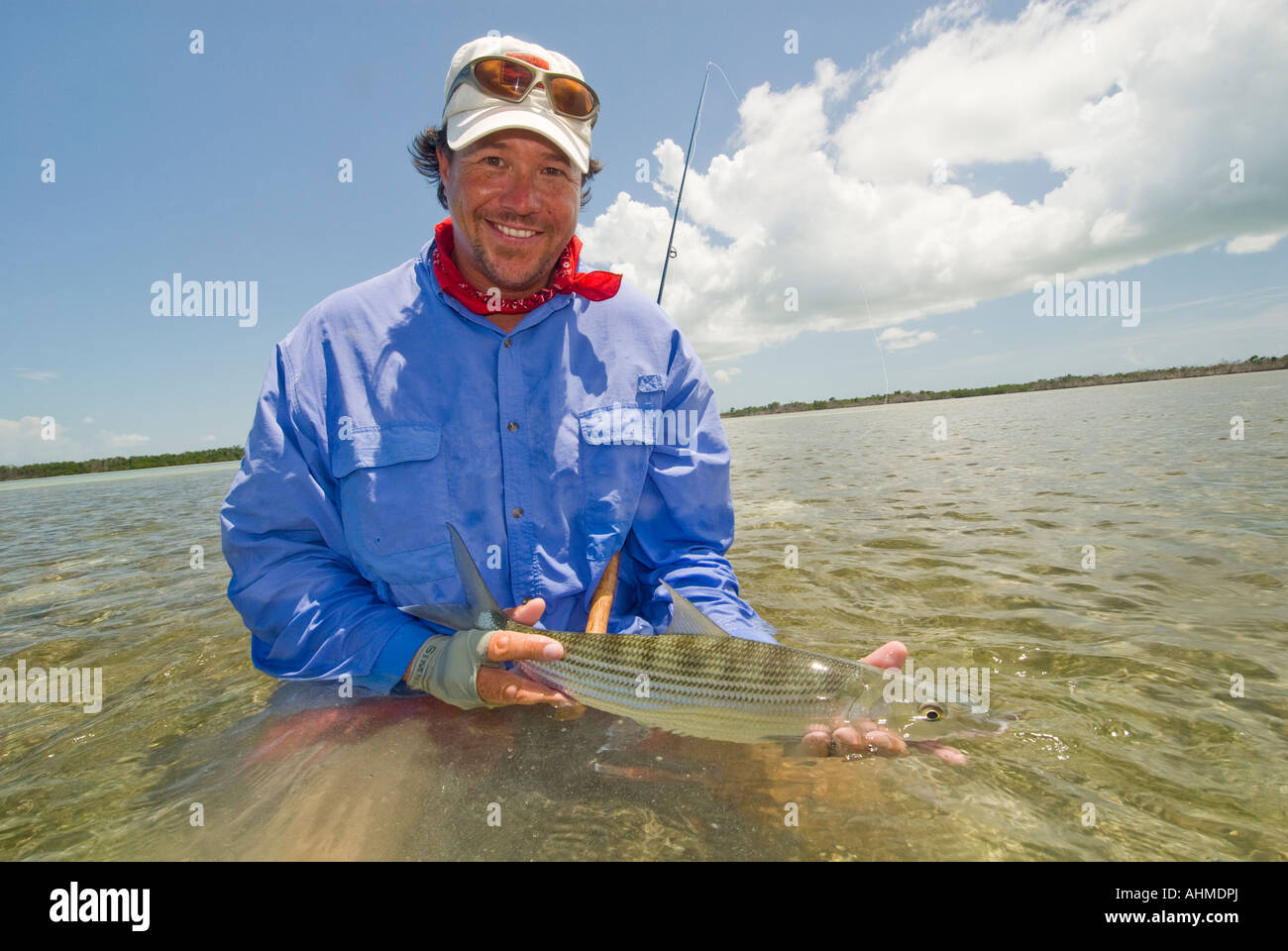 Florida Key Happy  fisherman landing and releasing a bonefish while fly-fishing the flats of the Caribbean ocean Stock Photo