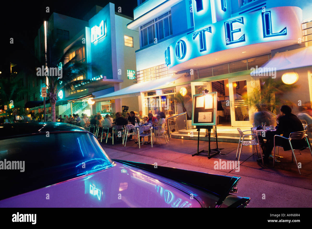 Florida, Miami, South Beach Art Deco. Street at night, neon lights, purple car and people dining on the street in a sidewalk cafe. Stock Photo