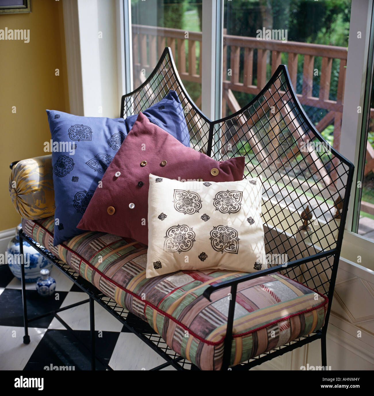 Wrought iron seat with cushions Stock Photo Alamy