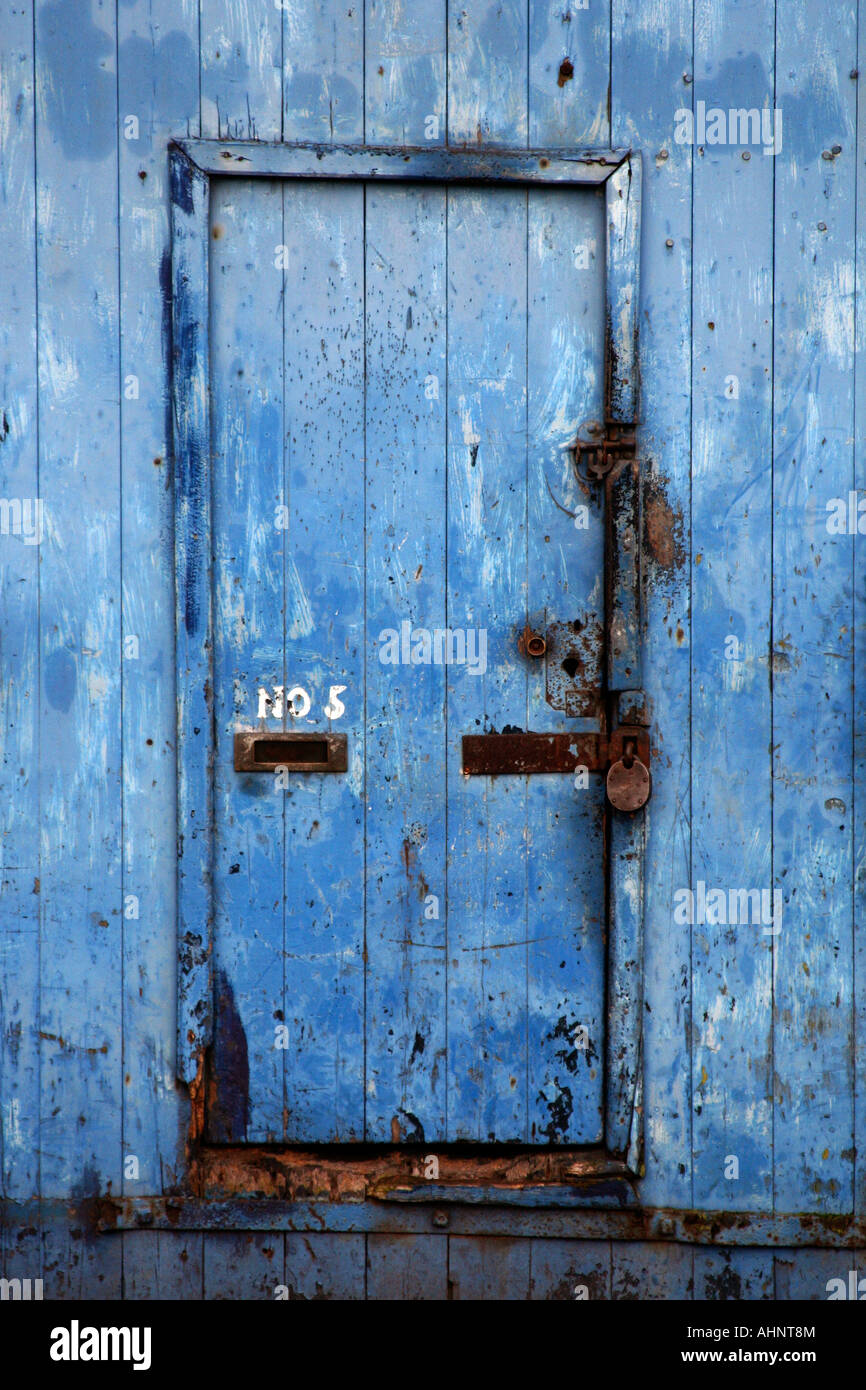 A weathered door showing rusted hinges and textured paint Stock Photo
