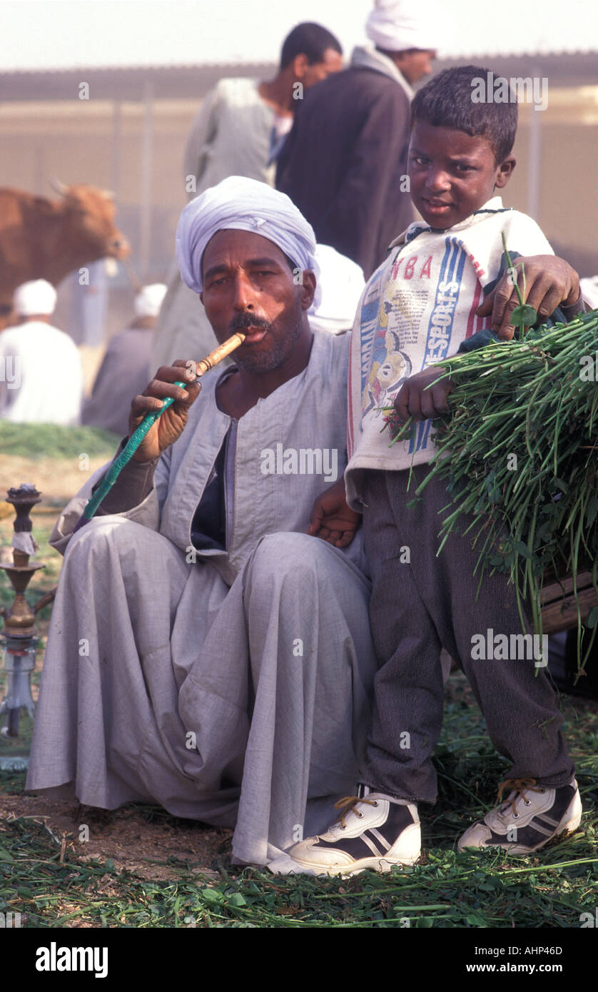Man at El Hebel camel market smoking a huqqah With his son Near Luxor Egypt Stock Photo