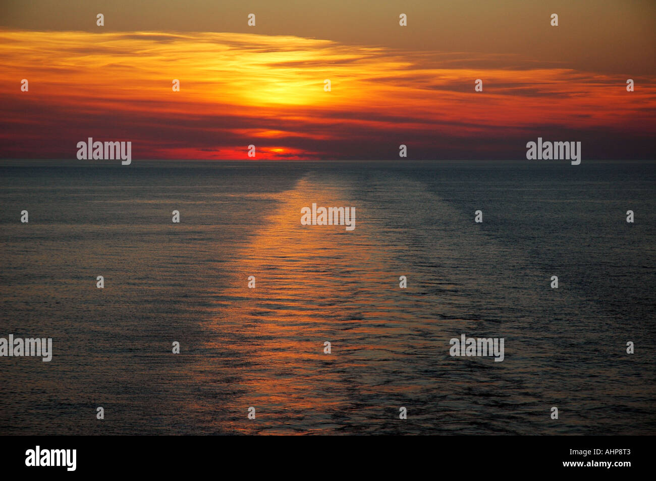 The sun setting, viewed from the stern of a crusie ship as it leaves ...