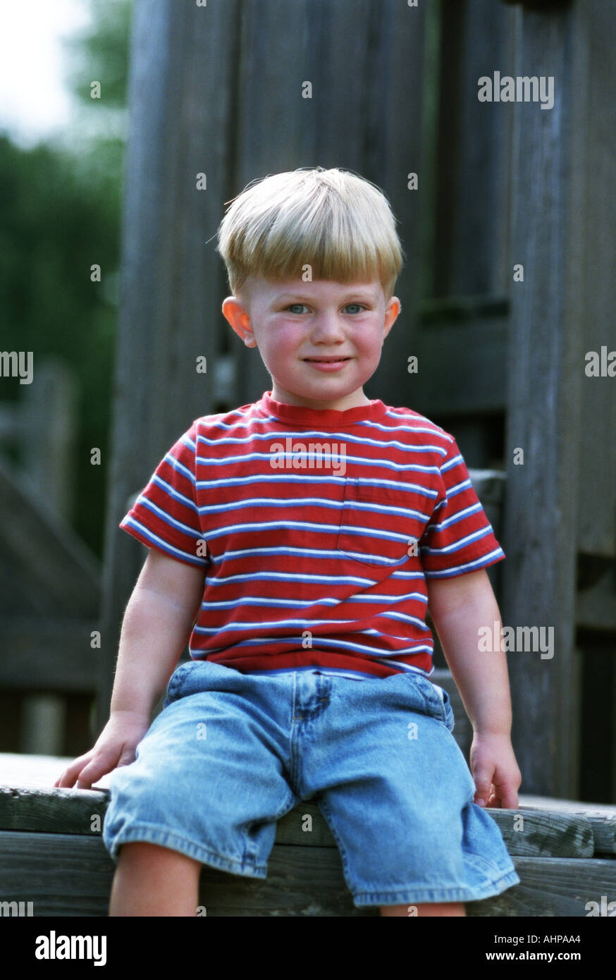 Small blonde boy smiling seated Portrait Stock Photo