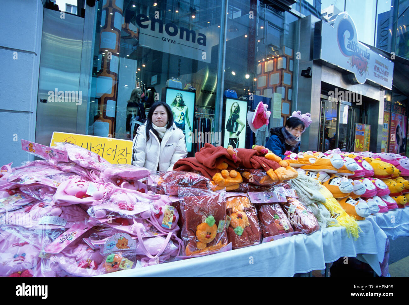Young lady selling cute cuddly soft toys and warm slippers at a street stall in Seoul city South Korea Asia in winter Stock Photo