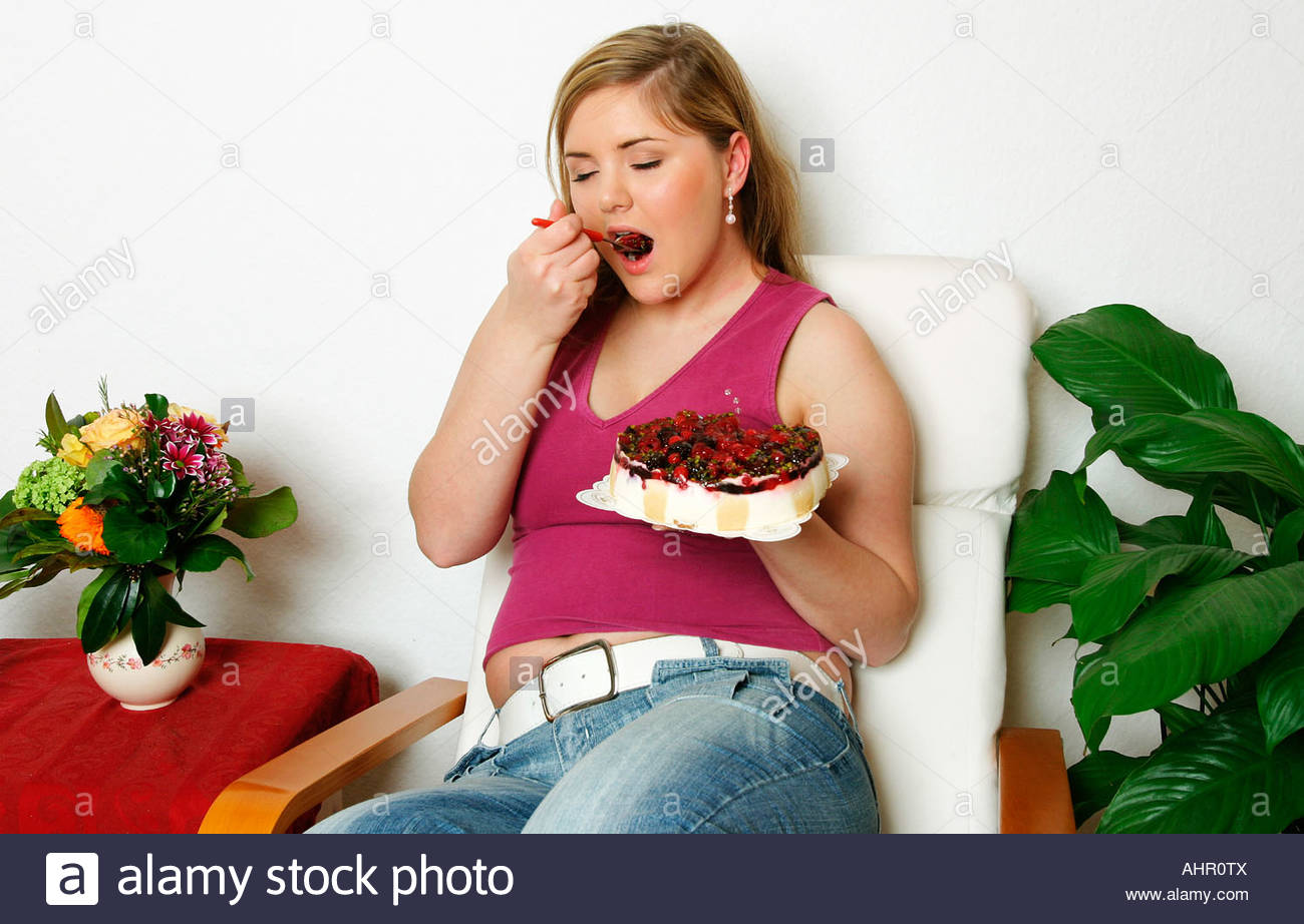 a-pudgy-young-woman-eating-a-fruit-cake-AHR0TX.jpg