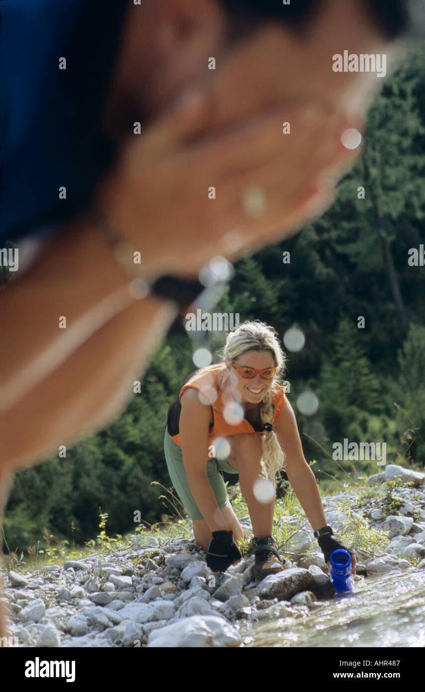 A woman collecting water and a man washing Stock Photo