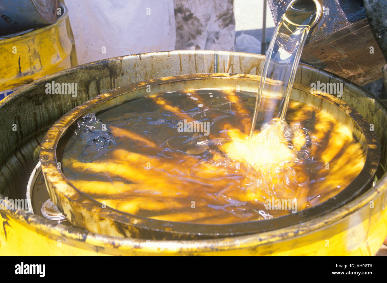 Workers pouring toxic wastes into a metal drum at waste cleanup site on Earth Day at the Unocal plant in Wilmington Los Angeles Stock Photo