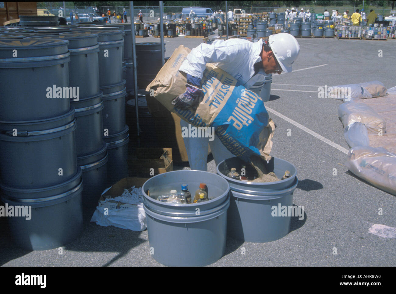 A worker pouring the contents of a bag into a container of waste materials at waste cleanup site on Earth Day at the Unocal Stock Photo