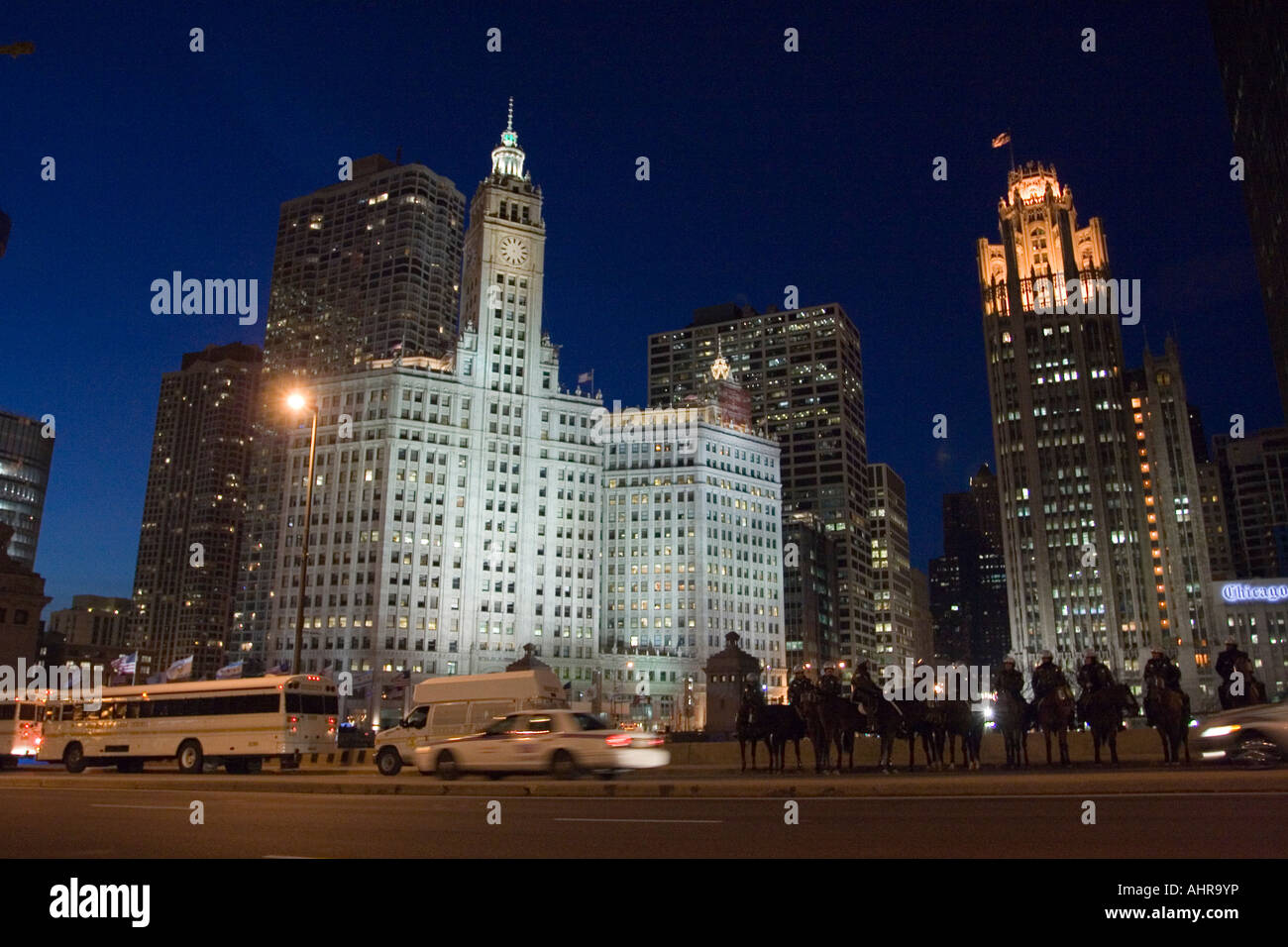 The Wrigley Building at night with a group of mounted policeman in the foreground in Chicago Stock Photo