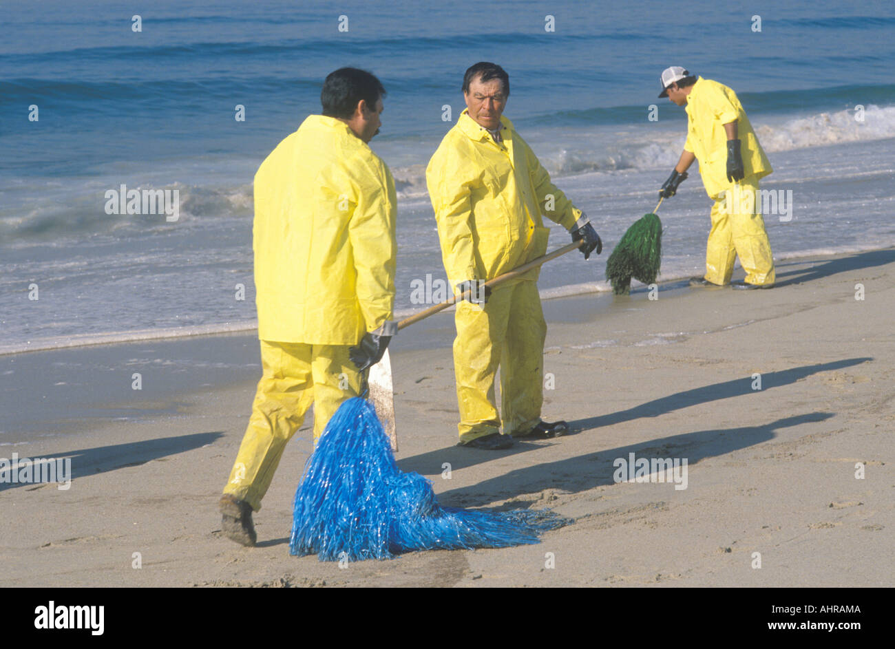Three oil cleanup workers cleaning up the beach with adsorbent material