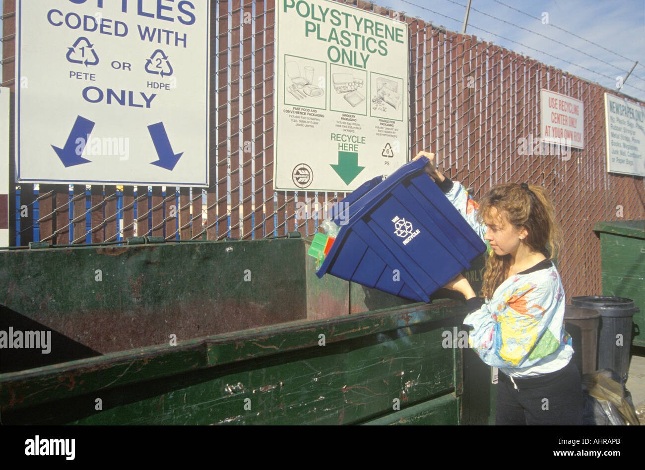 A woman recycling plastics in separate recycling containers at the Santa Monica Recycling Center CA Stock Photo