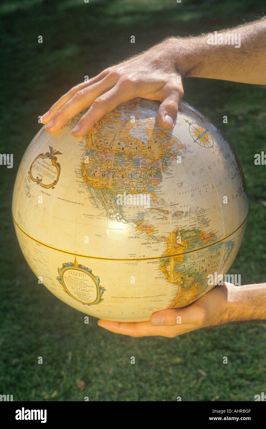 Hands holding a globe over a patch of grass Stock Photo