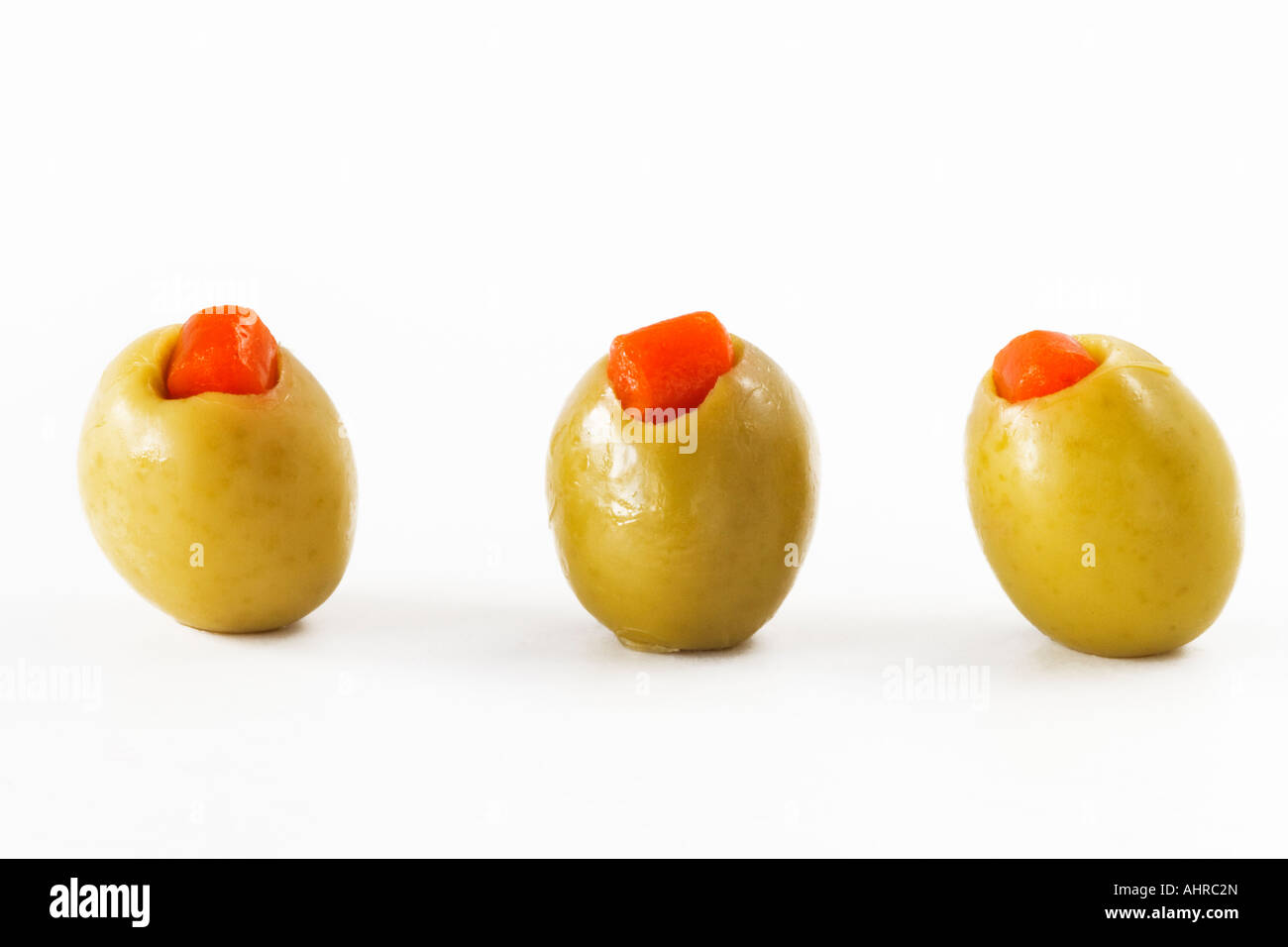 Three green olives in a row on white background Food still life Stock Photo