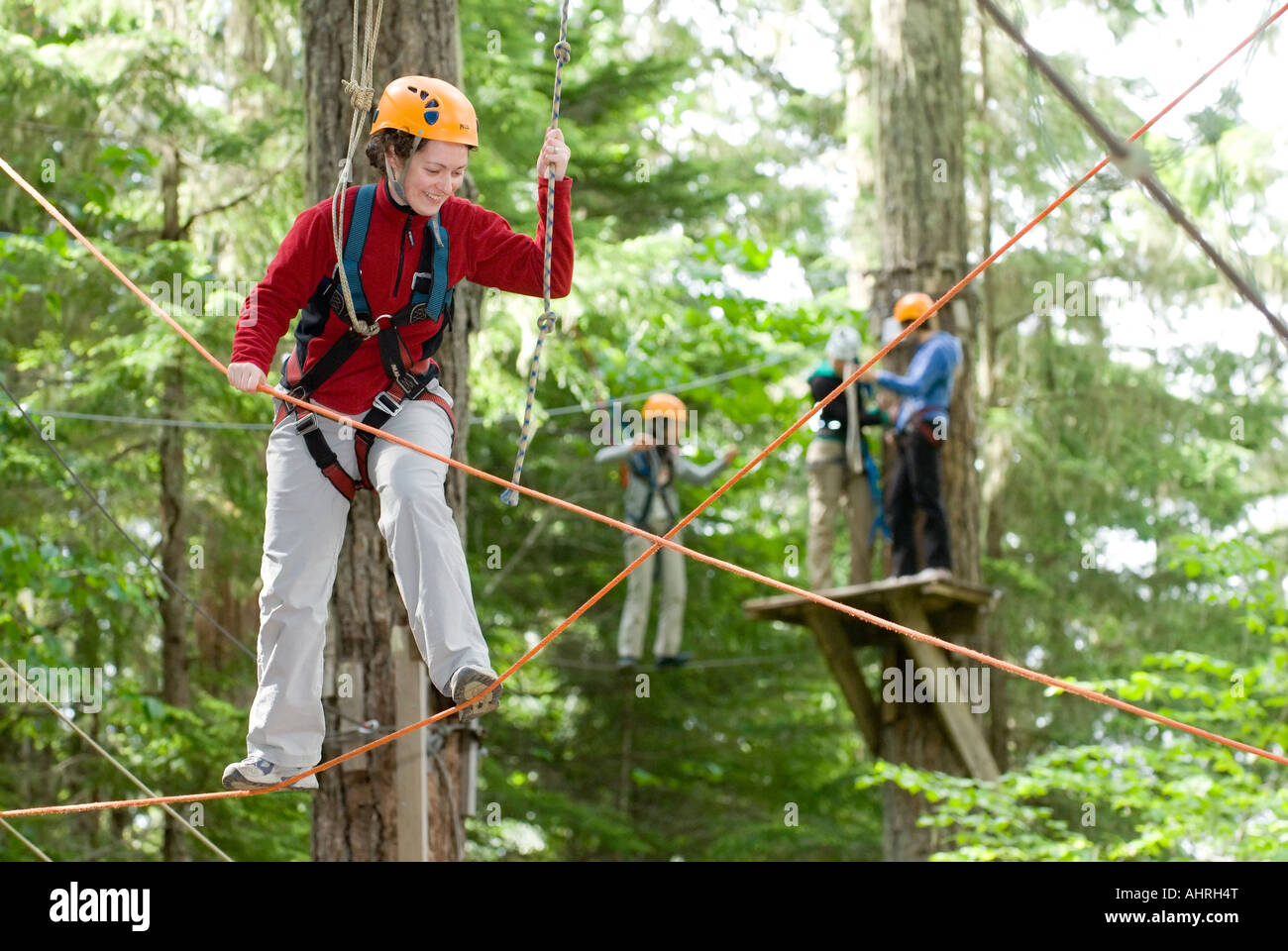 A woman works her way through a High Ropes course at the Strathcona Park Lodge on Vancouver Island BC Stock Photo