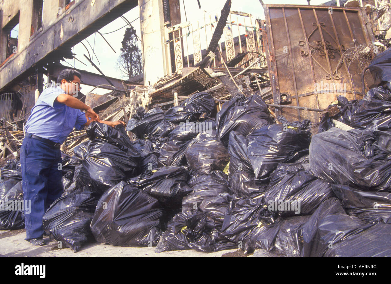 Man piling trash bags after 1992 riots South Central Los Angeles California Stock Photo