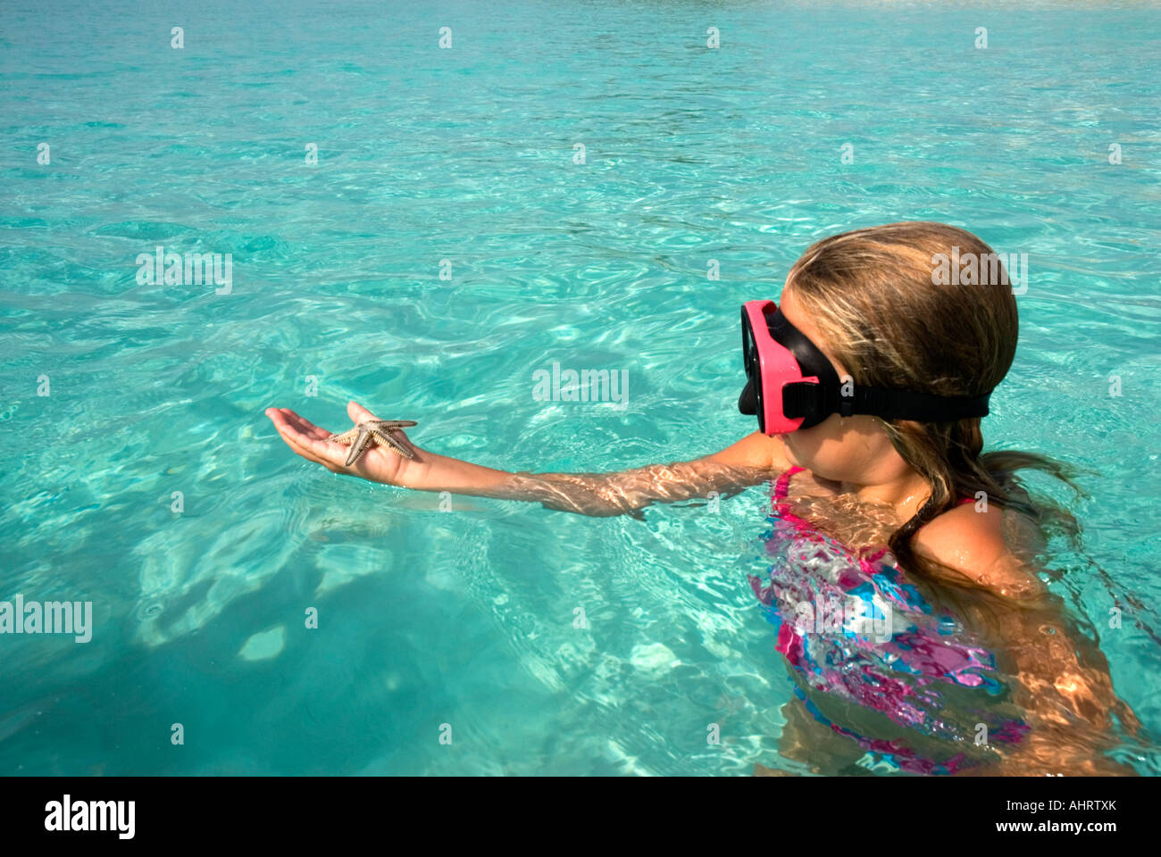 Girl holding starfish, Cape Santa Maria, Long Island, Bahamas Stock Photo