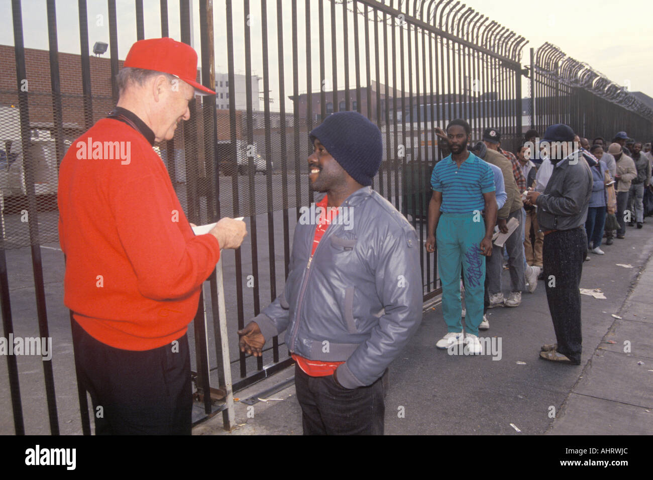 Father Joseph giving Christmas dollars to homeless men Los Angeles California Stock Photo
