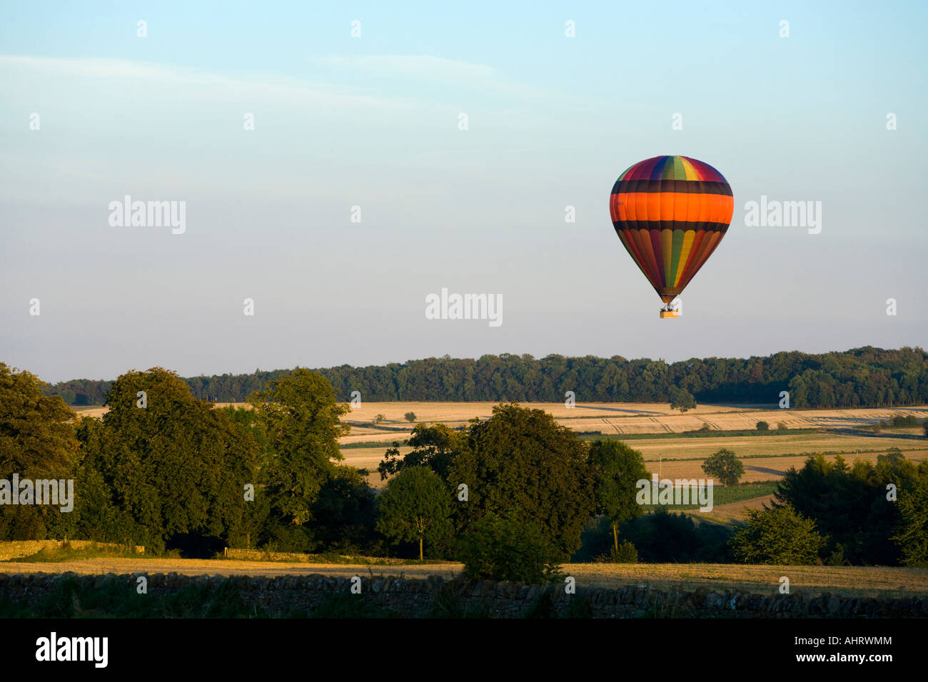A hot air balloon in the evening sunlight about to land near the Cotswold town of Chipping Campden, Gloucestershire Stock Photo