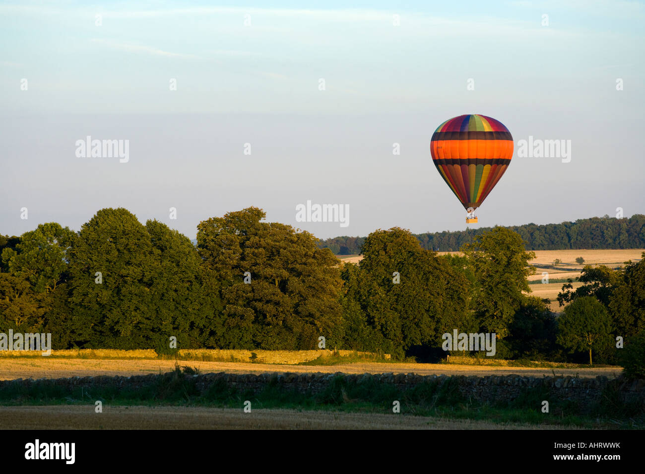 A hot air balloon in the evening sunlight about to land near the Cotswold town of Chipping Campden, Gloucestershire Stock Photo