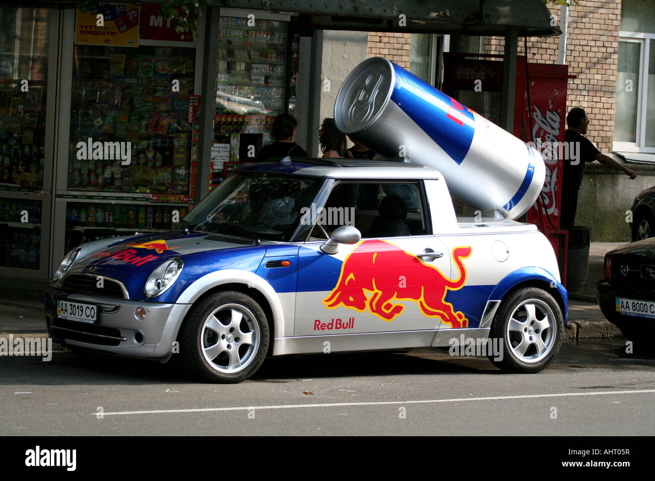Red Bull promotional Mini Cooper with a giant can on its roof parked in Kyiv, Ukraine, outside a convenience store. Stock Photo