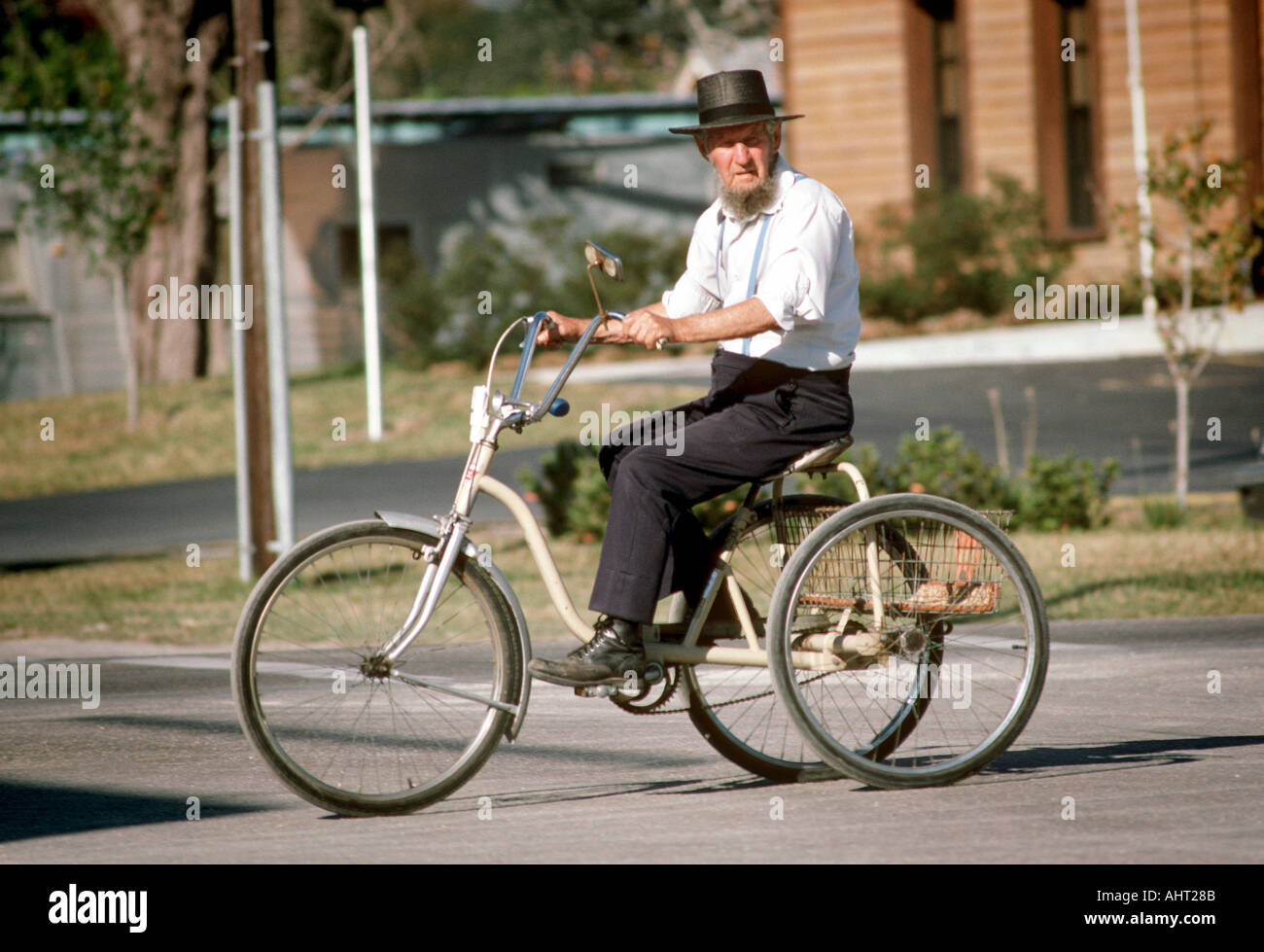 Amish male crosses a busy street on a three wheel tricycle Stock Photo