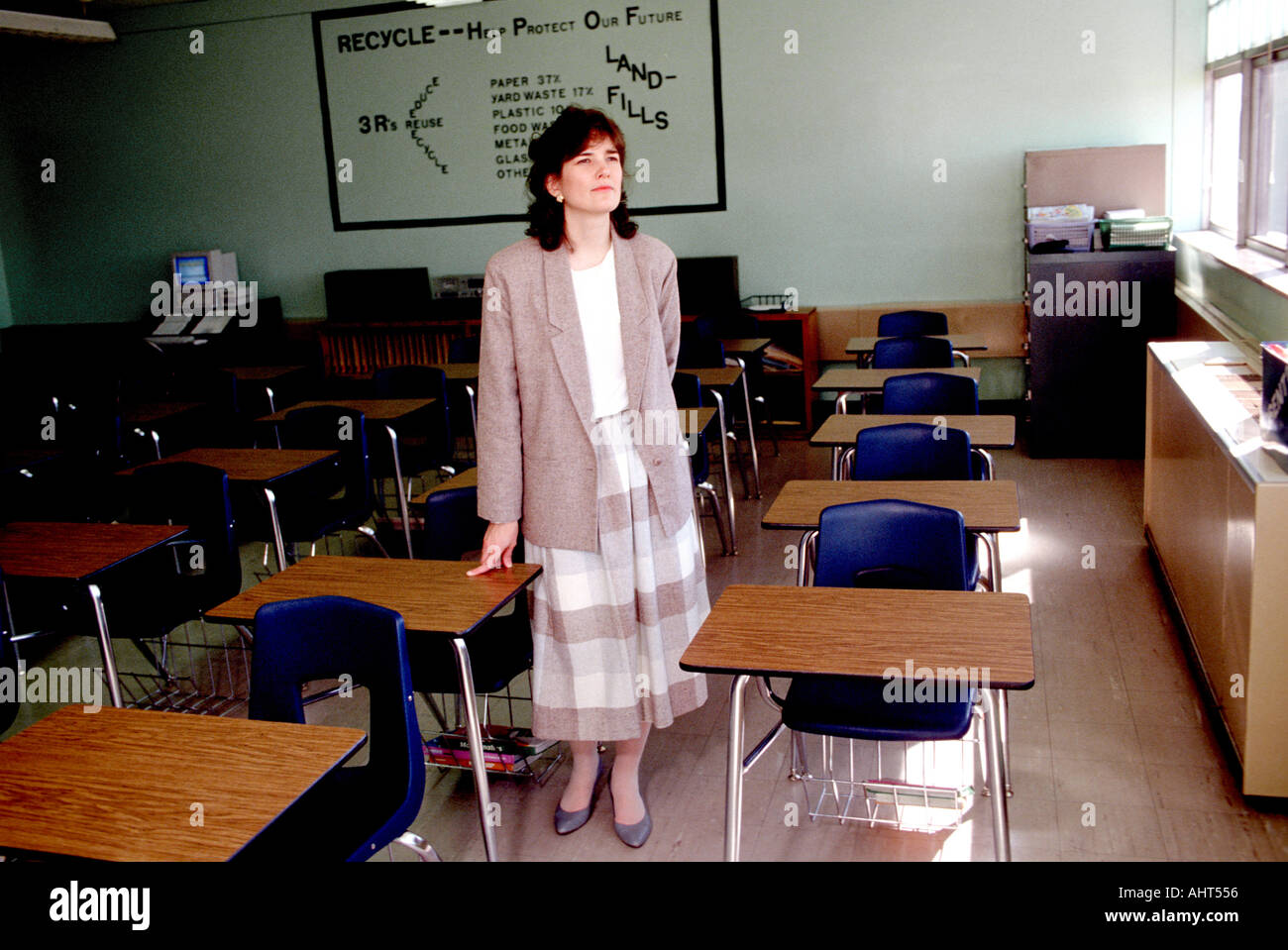 Female teacher alone in an empty classroom in a pensive mood Stock Photo
