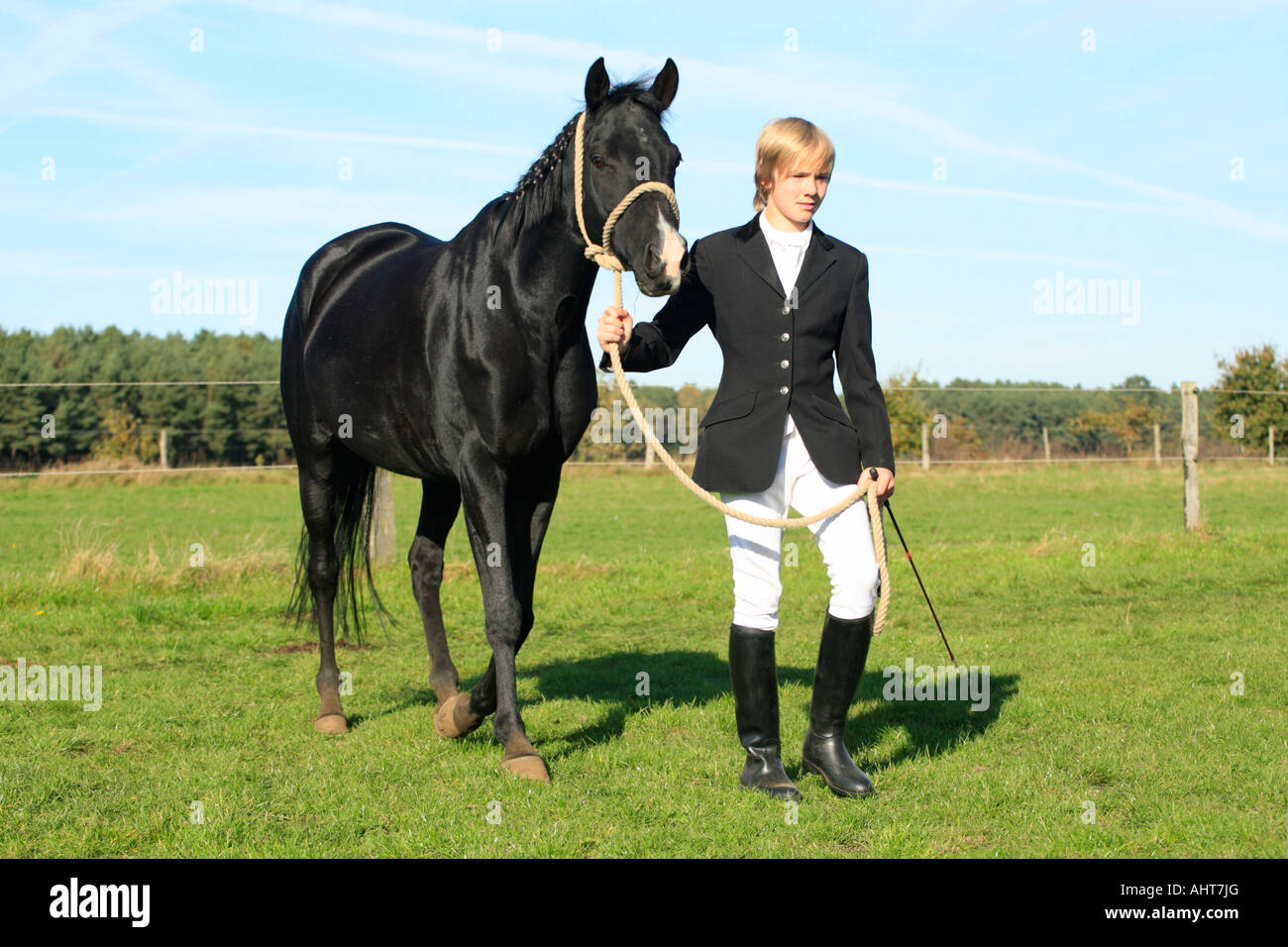young boy walking with his black stallion after a horse show Stock
