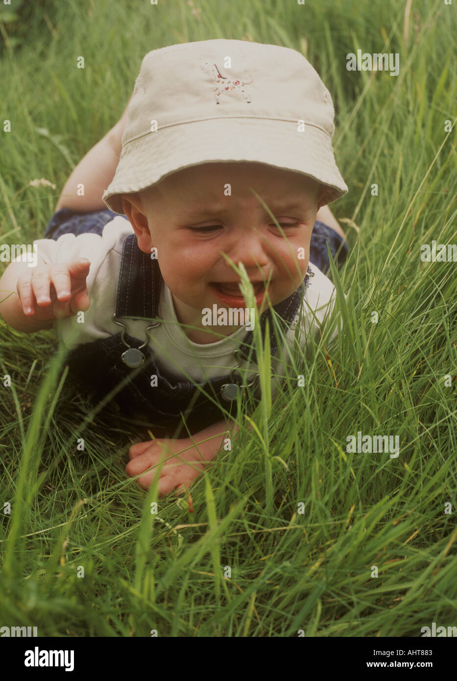 baby boy lying in the grass in the garden crying Stock Photo