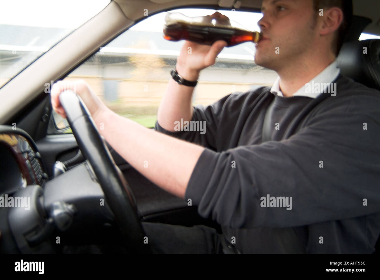 distracted car driver drinking soft drink drunk beer at the wheel fast