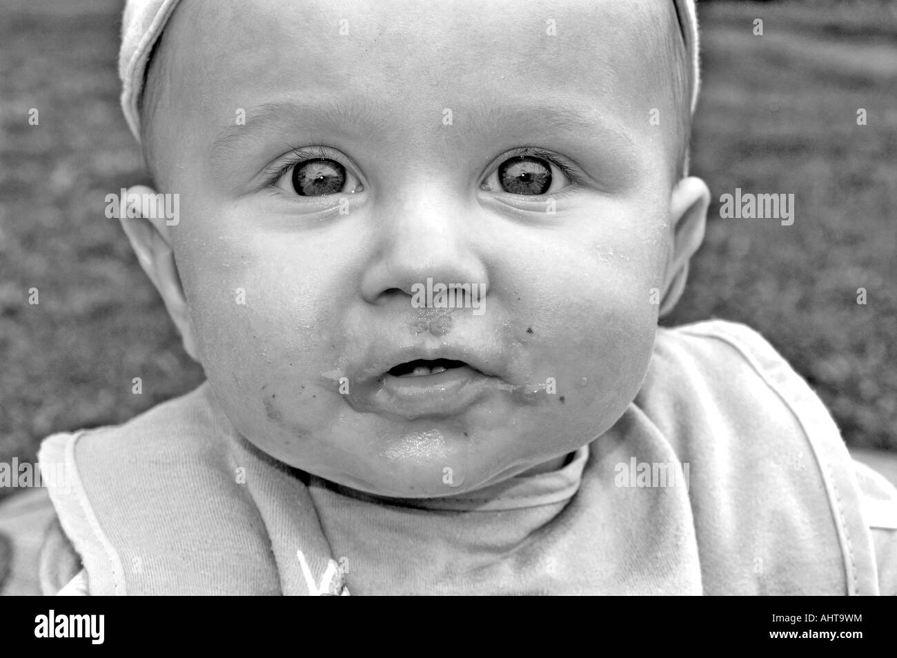 baby boy wearing a bib with food round his face in black and white Stock Photo