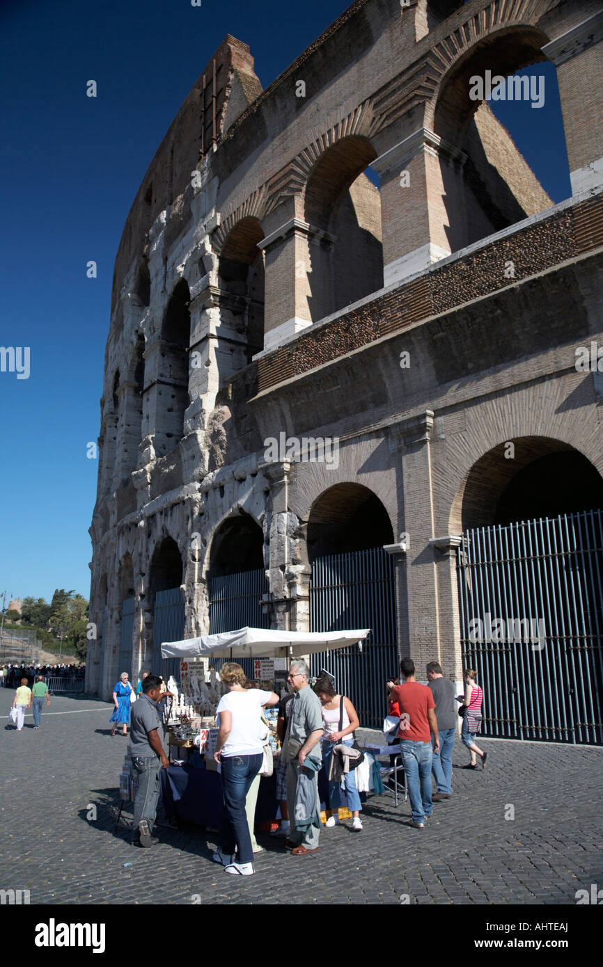 Tourists examine items on a tourist souvenir stall outside the Colosseum Rome Lazio Italy Stock Photo