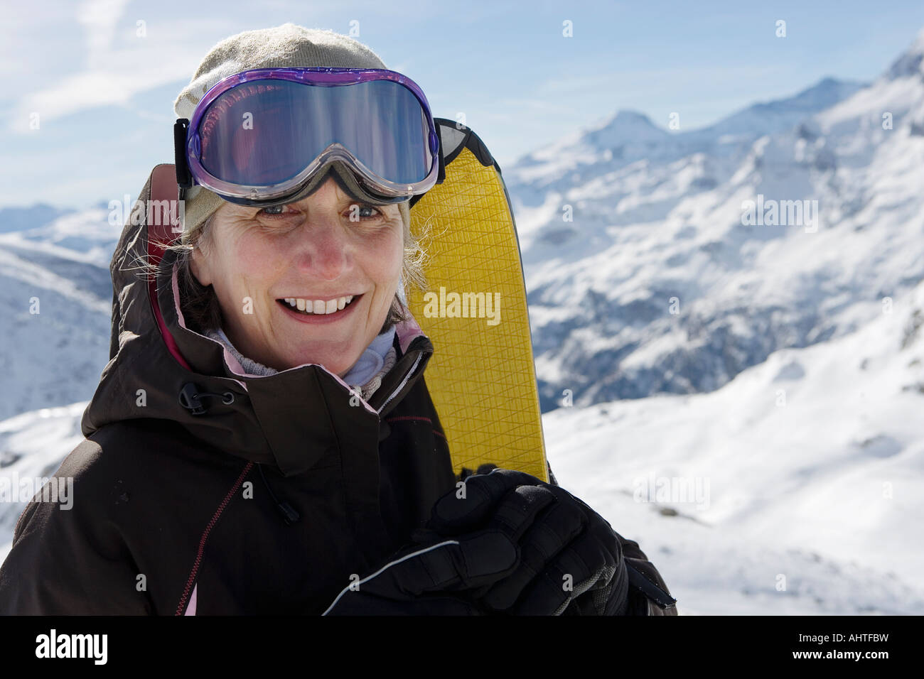 Mature female skier holding Skis on mountain, close-up, portrait Stock Photo